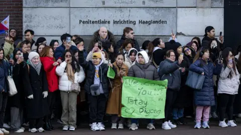 Getty Images A group of Duterte supporters gather outside the detention centre in Scheveningen, The Hague. One of them holds up a green banner that reads, "We love you!"