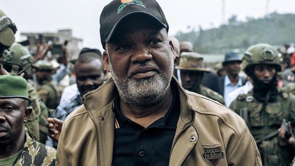 Congo River Alliance Corneille Nangaa, wearing black cap, black T-shirt and brown jackets, arrives at the Stade de l&#39;Unite in Goma on February 6, 2025. He is surrounded by M23 fighters.