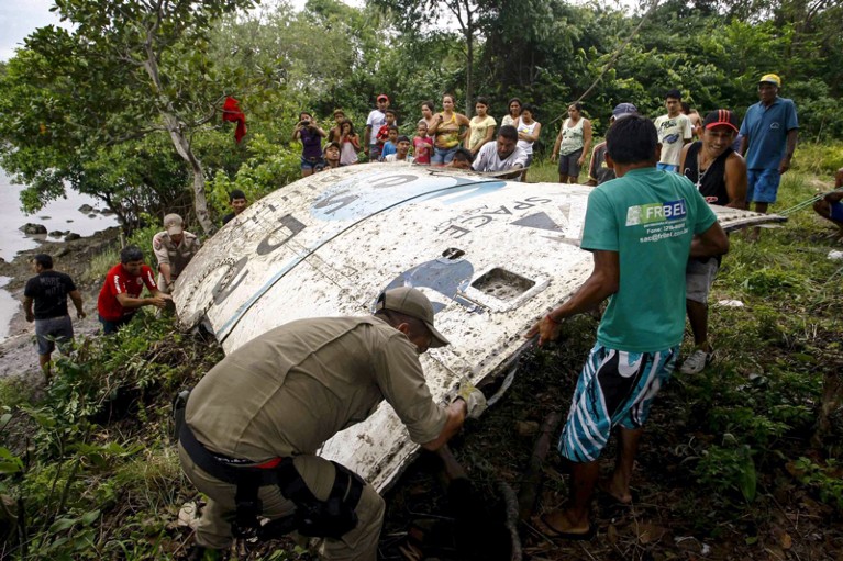 People gather on the bank of a river to lift a large piece of space wreckage bearing the logo of the UK Space Agency and Arianespace which crashed in French Guiana