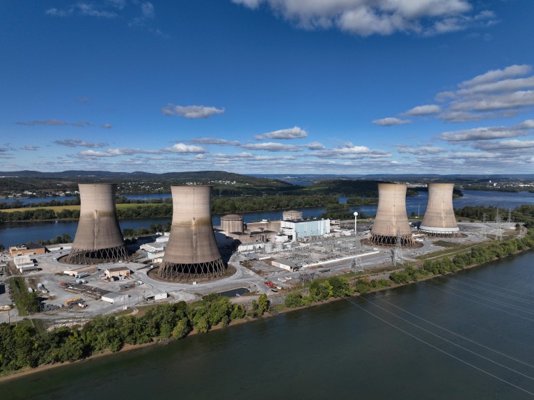 Four cooling towers, surrounded by other buildings, situation on an island in a river