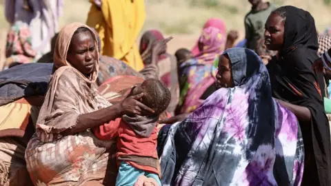 Getty Images Displaced Sudanese women and children gather at a camp near the town of Tawila in North Darfur on February 11, 2025