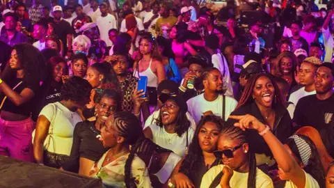 The Plug Entertainment A crowd of young people in the audience looking at the stage at a music event during Detty December in Lagos, Nigeria, 2024