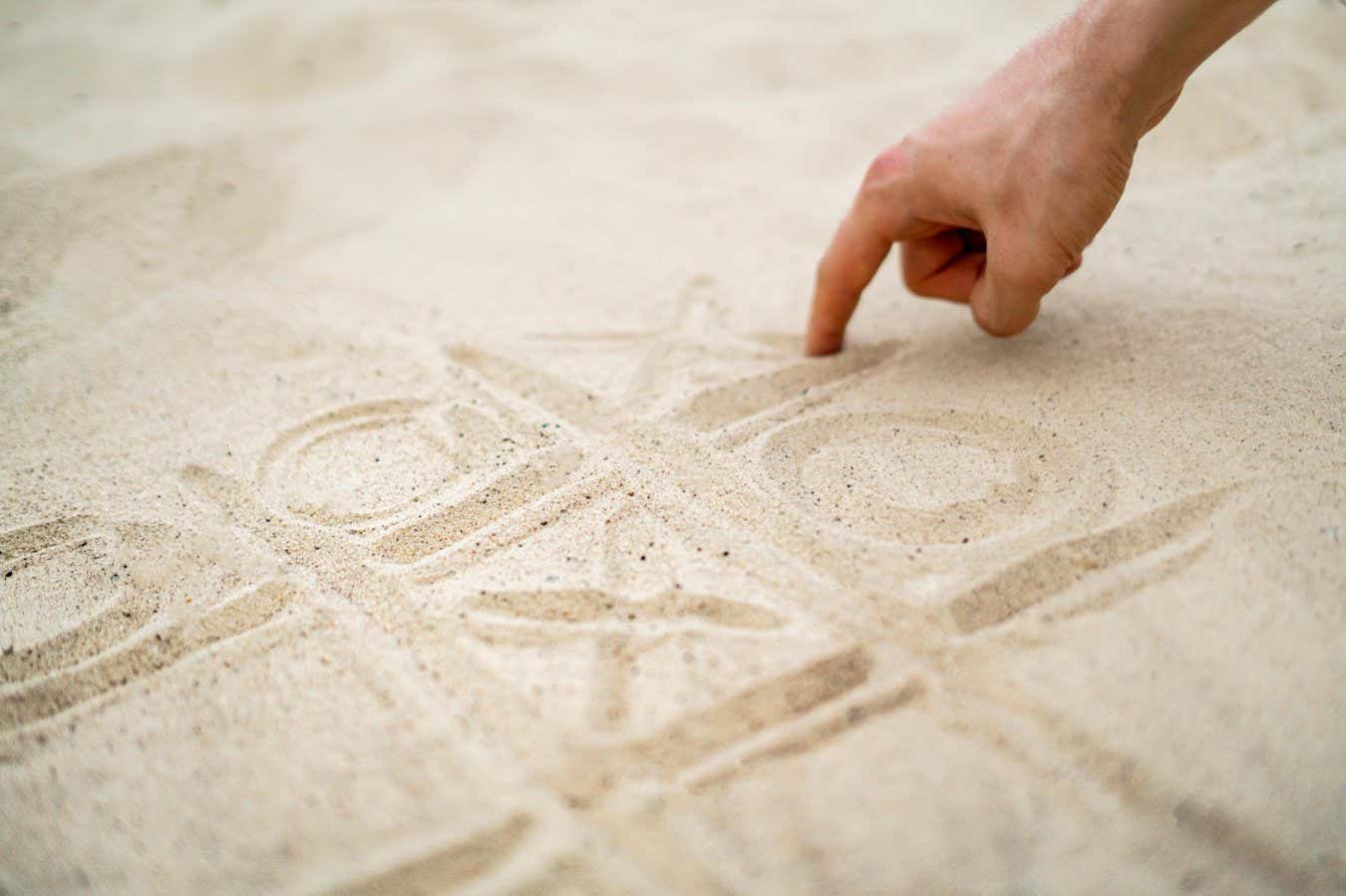 WP9M9W hand drawing tic tac toe playing on the sand in summer beach