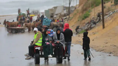 Getty Images Male and female Palestinians sitting on a trailer in rainy weather