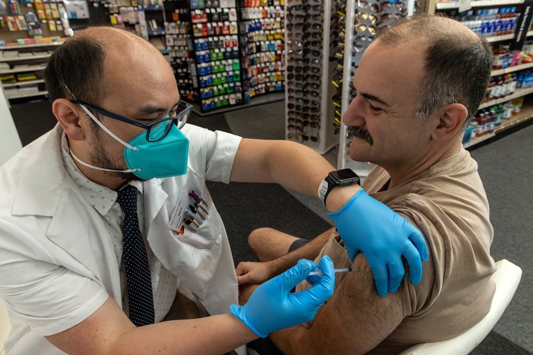 A pharmacist administers a new covid mRNA vaccine to a patient in a Pharmacy in the U.S.