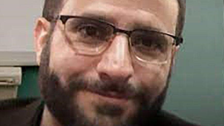 A photo of Farouk Abdulhak. The picture is closely cropped to his face and low quality. He is wearing glasses and smiling at the camera 