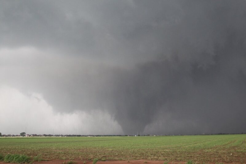 Enhanced Fujita Scale: A huge, wide funnel cloud beneath low clouds, touching a field.